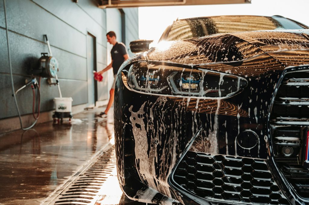 A person washing their car in a manual service car wash bay.