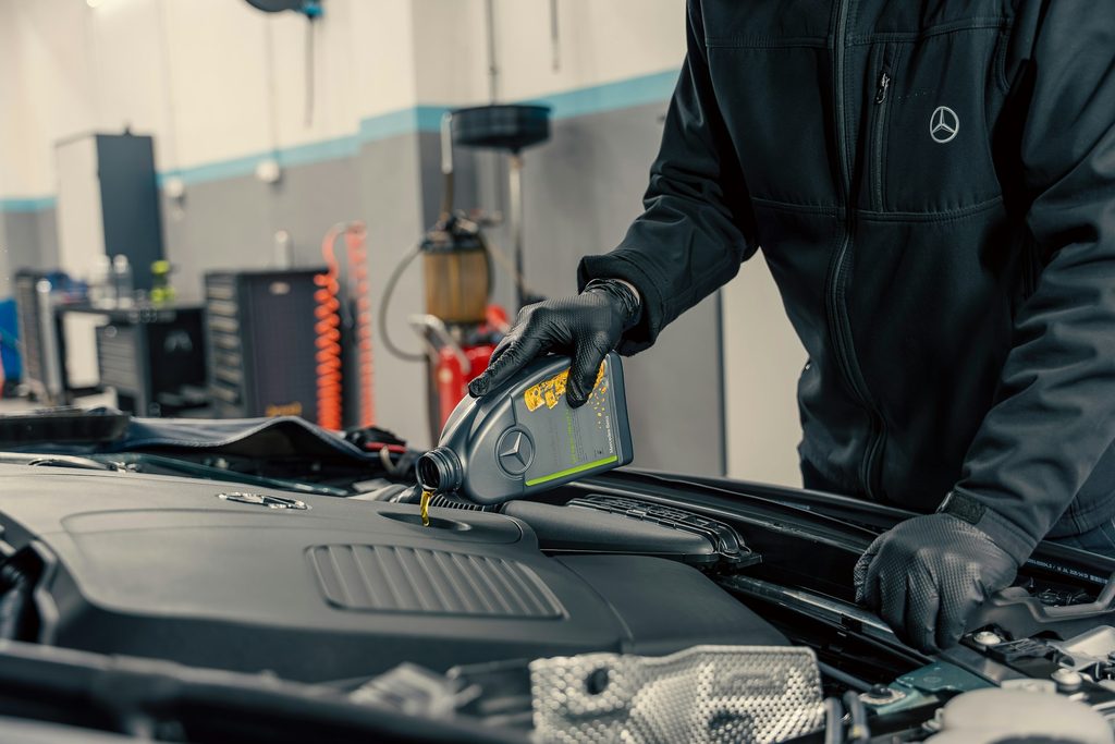 An auto care technician pours motor oil into the engine of a Mercedes. Repeatable processes and standardized facilities make for excellent franchise candidates.
